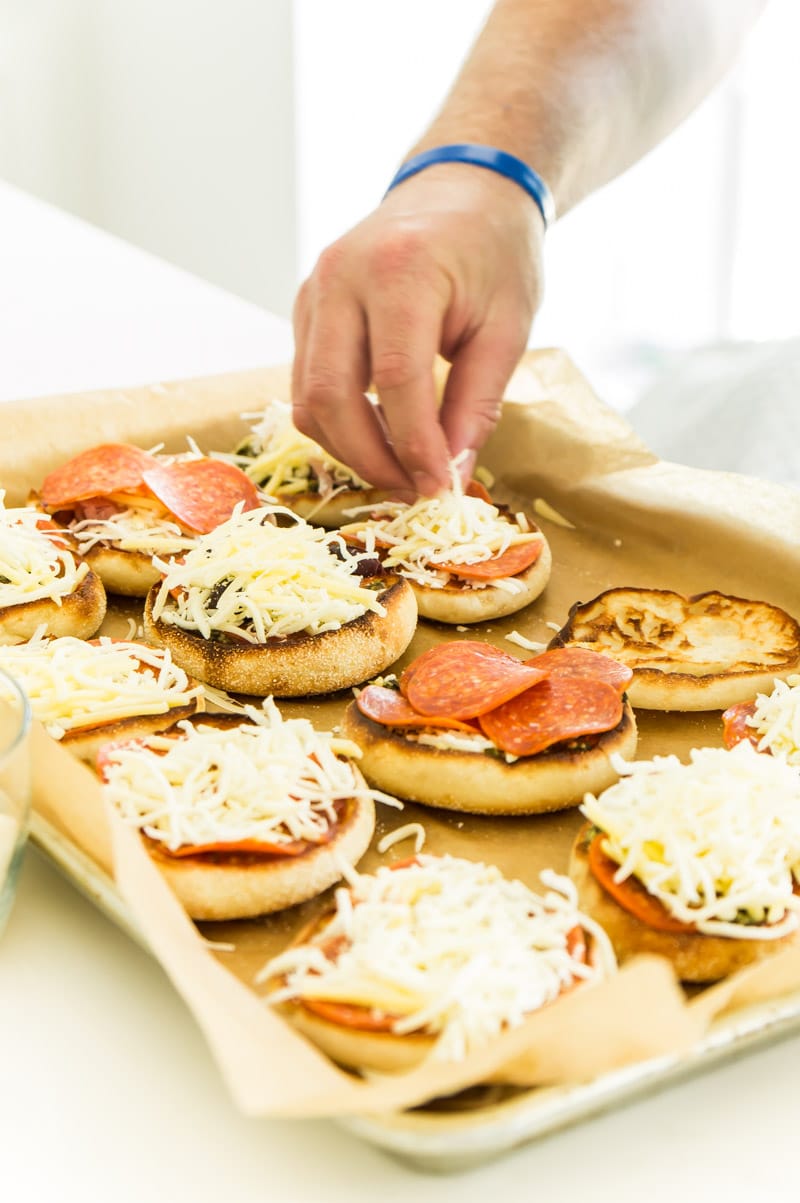 Adding toppings to English muffin pizzas