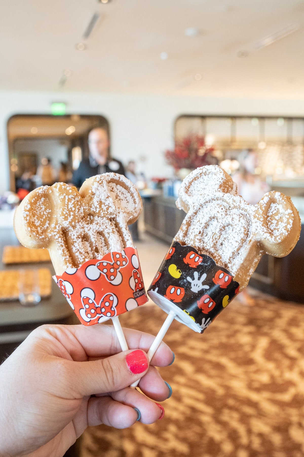 Hand holding two Mickey waffle dipper sticks