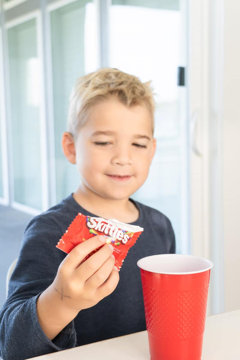 Pouring Skittles into a cup for a Gratitude Skittles Game