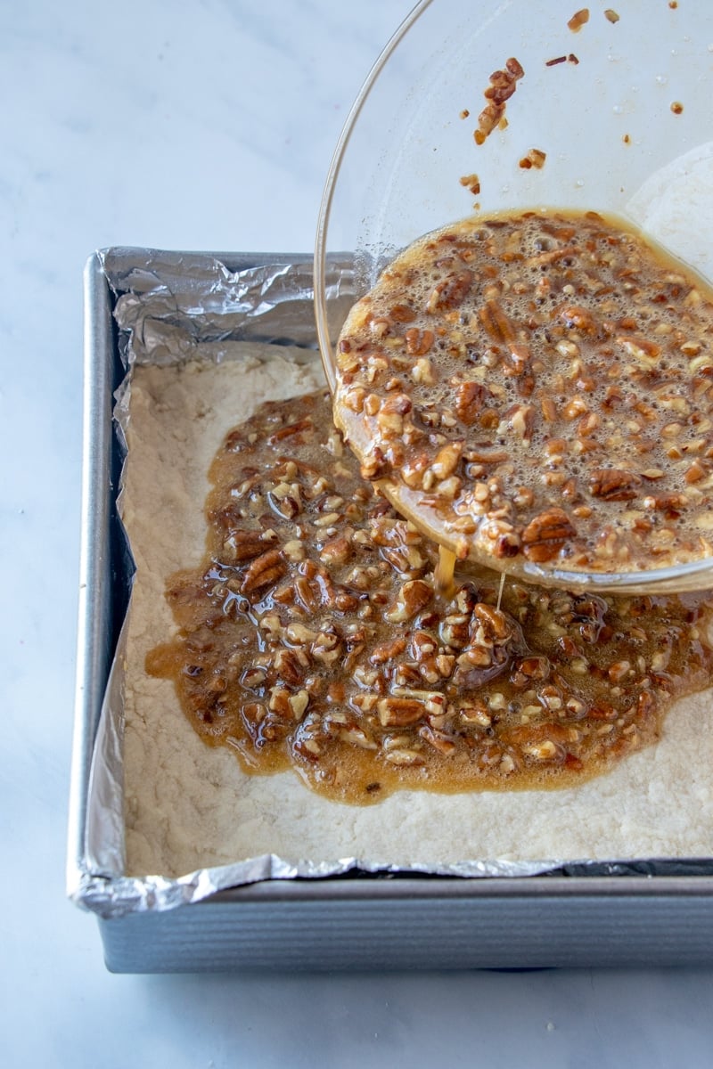 Pouring pecan pie bars onto shortbread crust