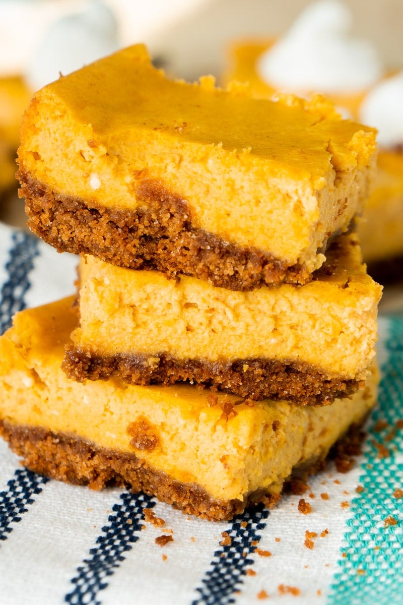 piled pumpkin cheesecake bars with a graham cracker crust