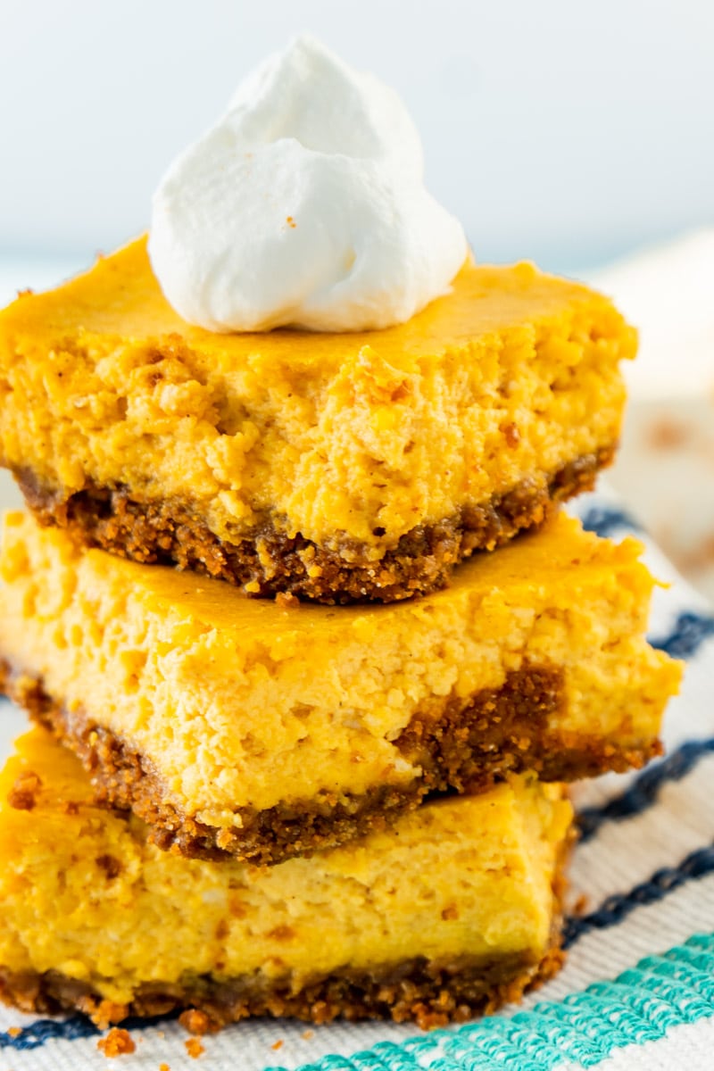 stacked pumpkin cheesecake bars with a graham cracker crust