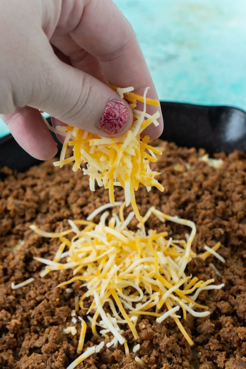 sprinkling cheese on queso fundido