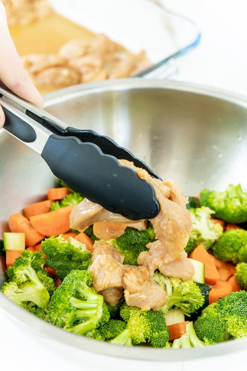 Adding marinated chicken to a teriyaki chicken sheet pan recipe