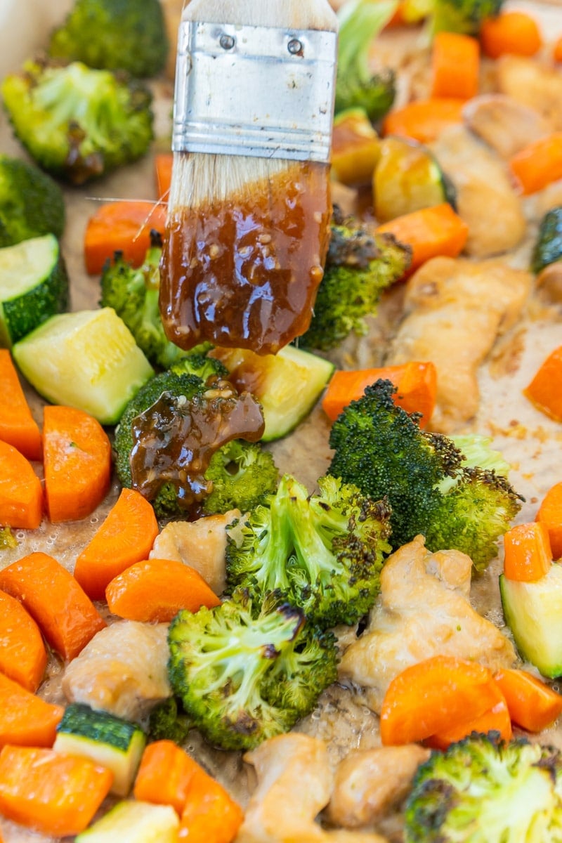 Adding teriyaki glaze to sheet pan teriyaki chicken