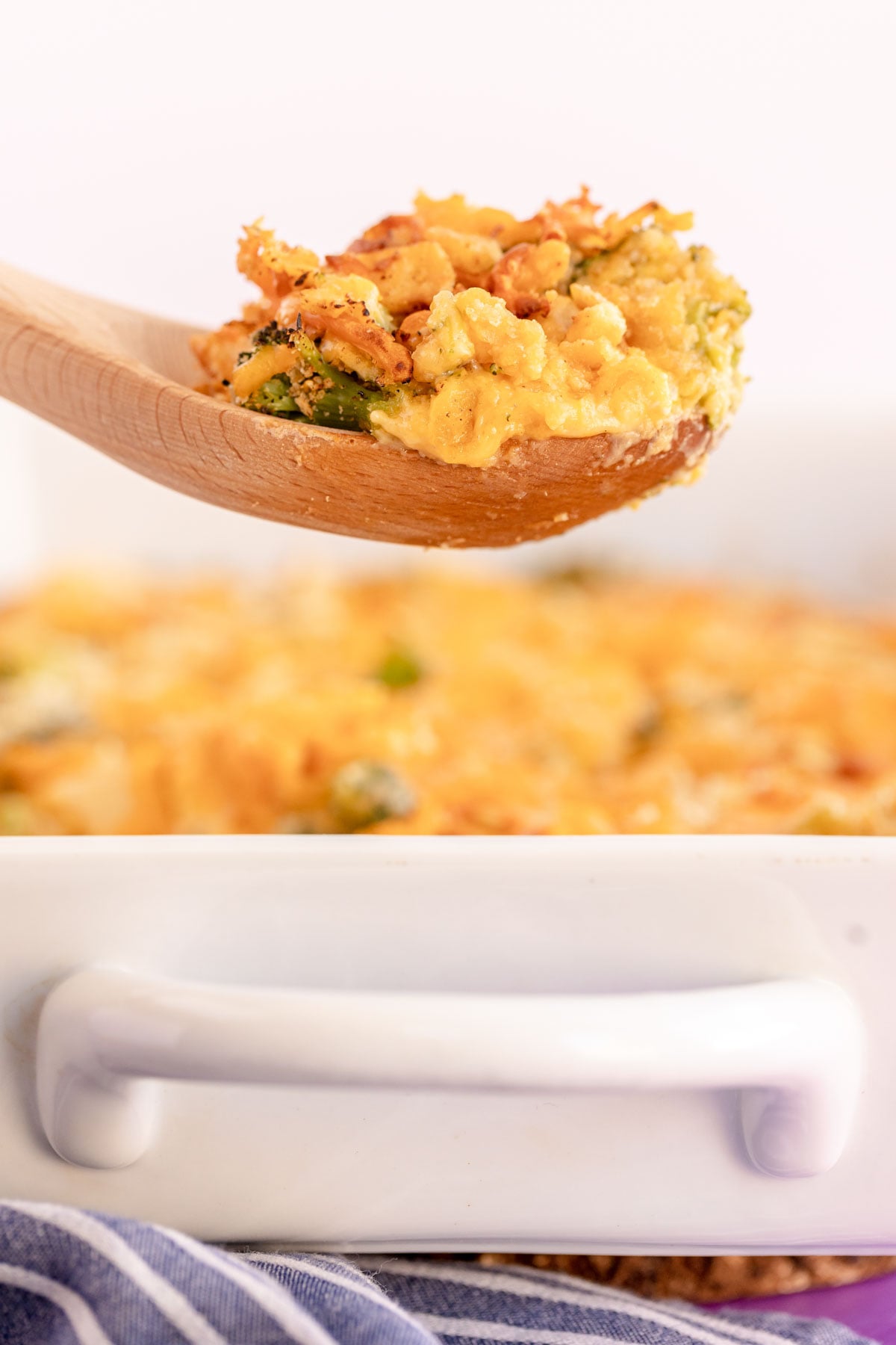spoon full of broccoli chicken casserole with ritz crackers above a casserole dish