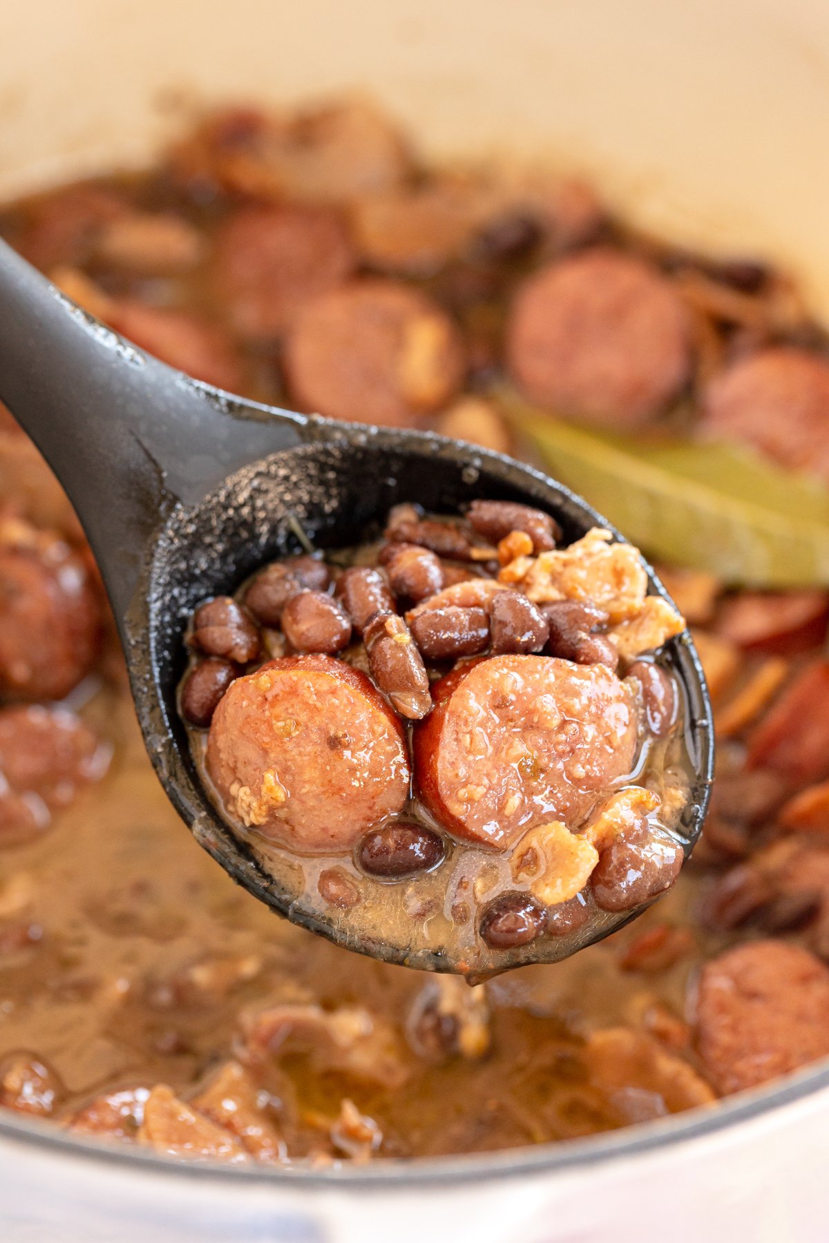 spoon full of Brazilian feijoada over a pot full 