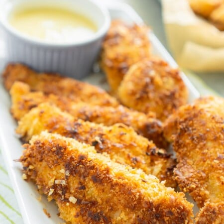 White plate full of coconut chicken tenders with a pina colada dipping sauce