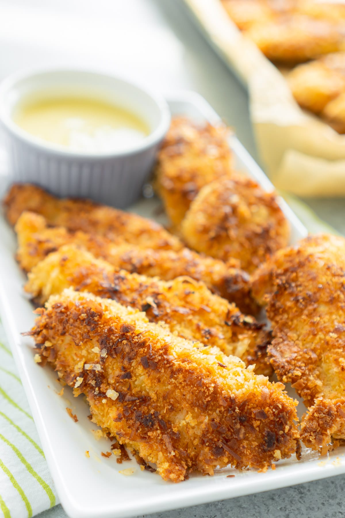 White plate full of coconut chicken tenders with a pina colada dipping sauce