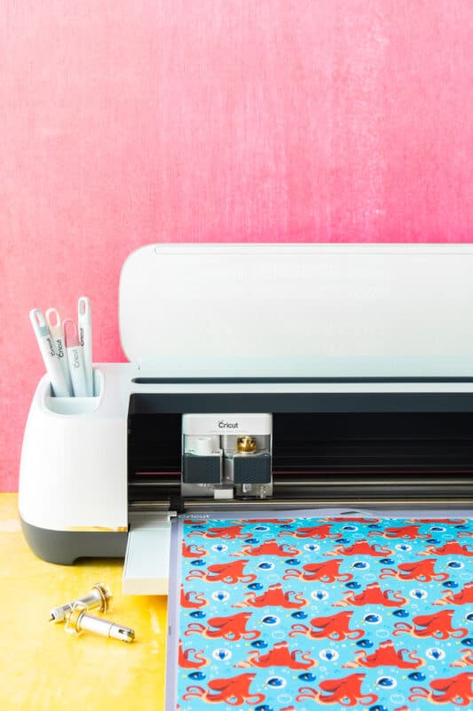 Cricut Maker on a yellow table with a pink background