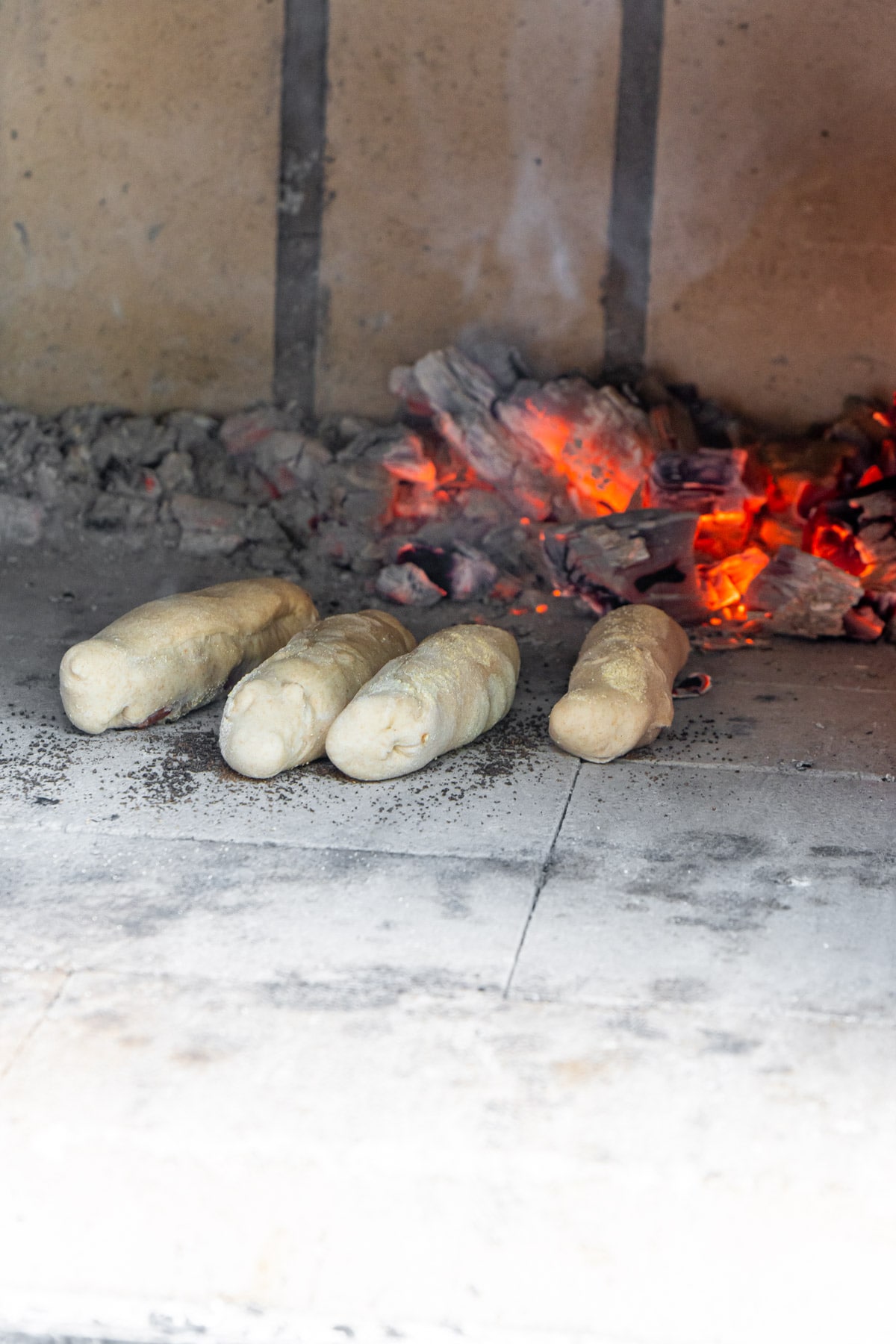 Four pepperoni rolls in a brick oven with fire in the background