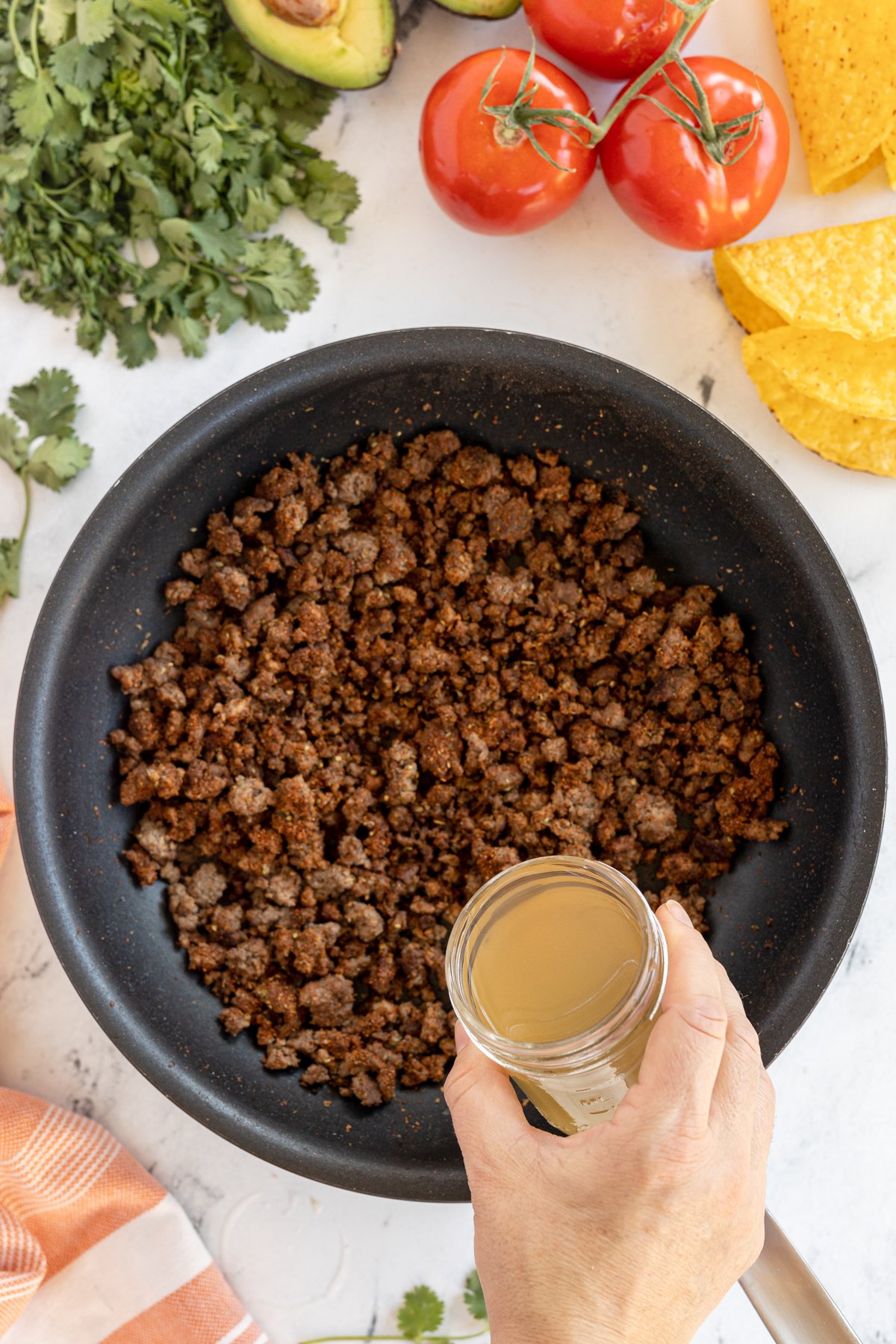 pouring broth into taco meat