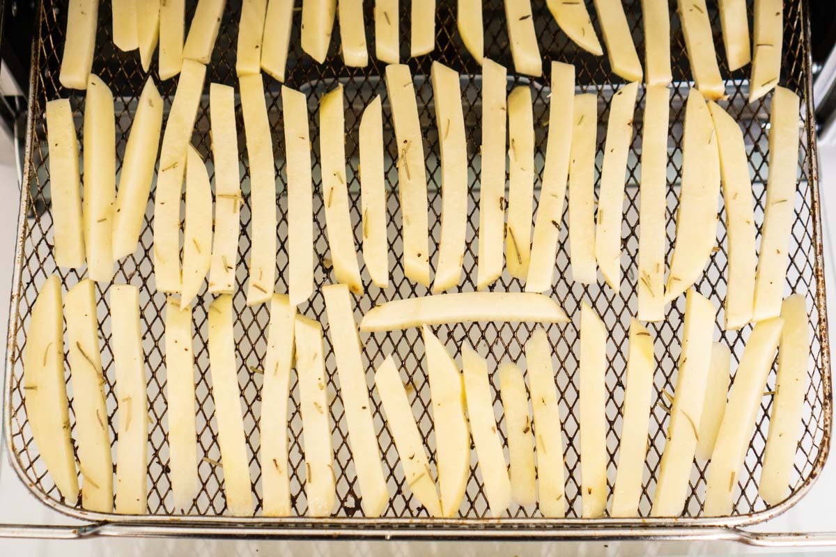 Potatoes cut like french fries on an air fryer baking rack