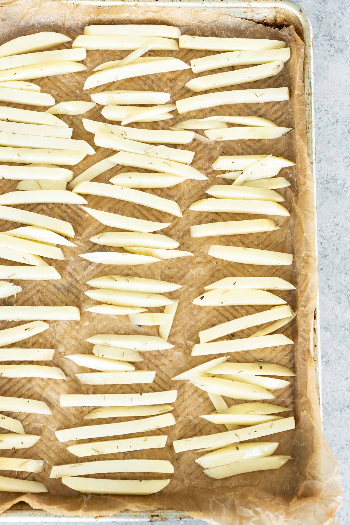 Potatoes cut like french fries on a baking sheet with parchment paper