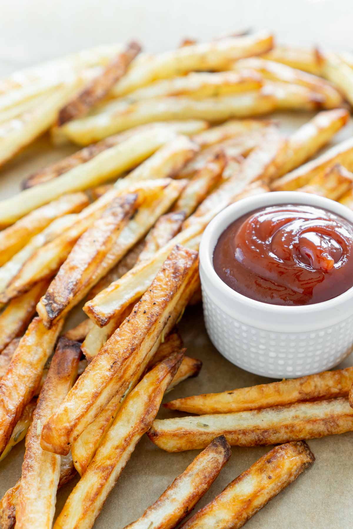 A pile of air fryer fries with a small white cup of ketchup