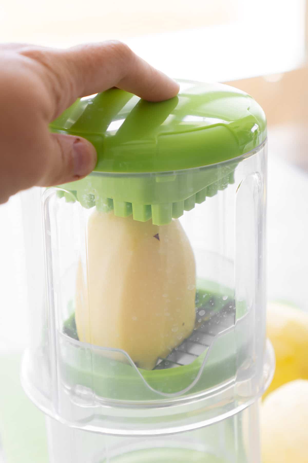 A hand holding a potato cutter with a potato inside