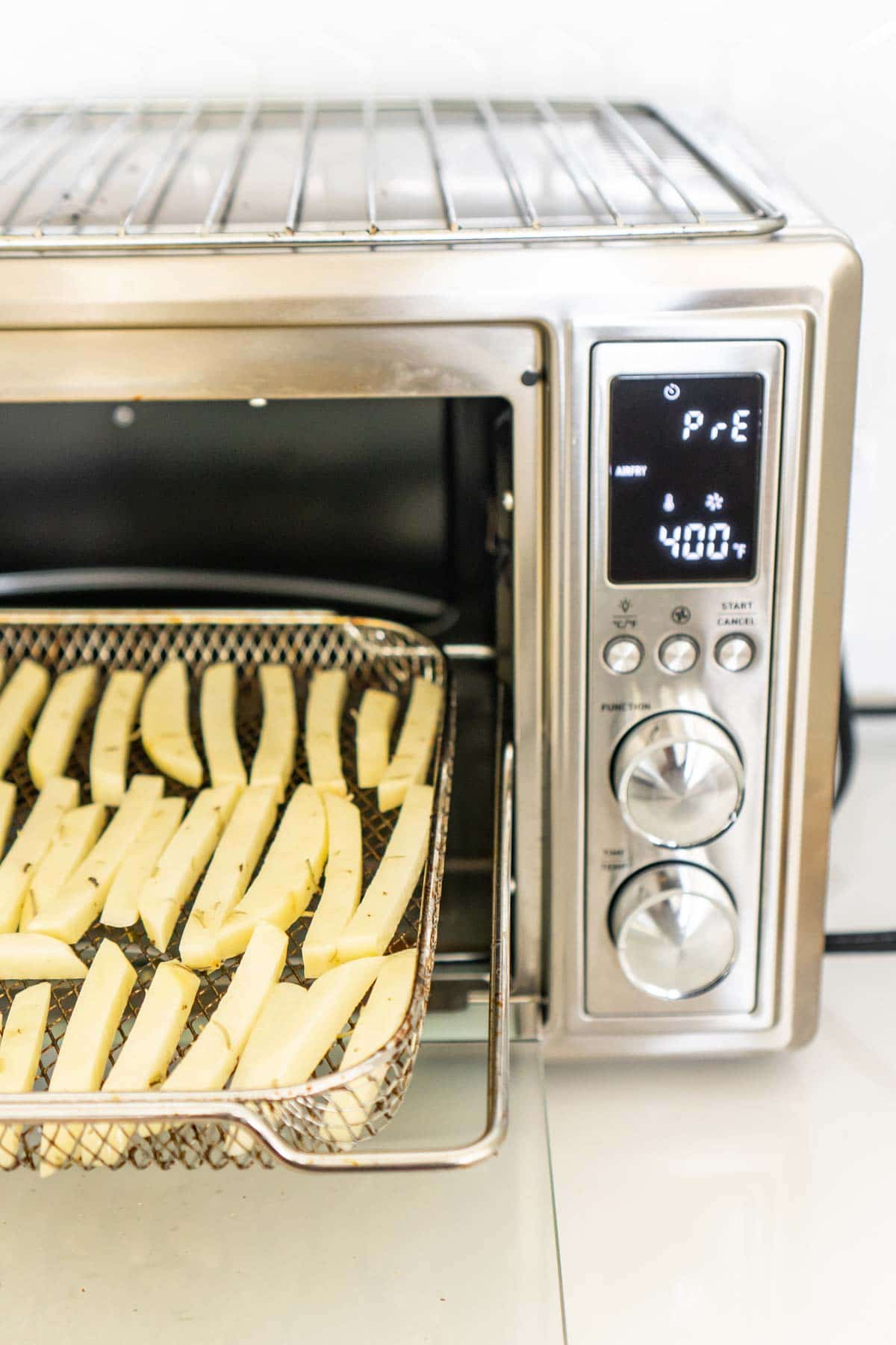 A cosori toaster oven air fryer with a rack full of cut potatoes