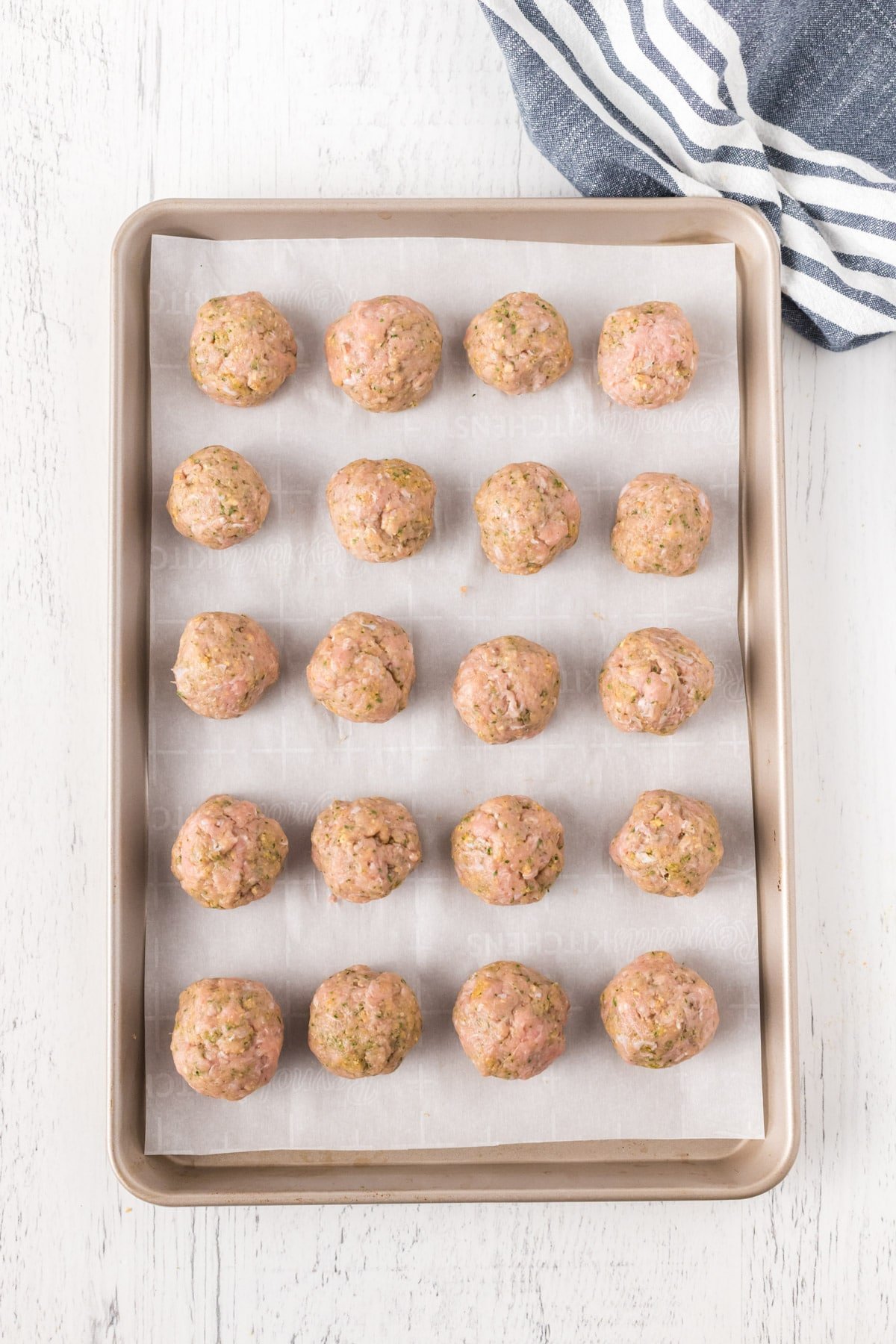 Rolled turkey meatballs on a baking sheet with parchment paper