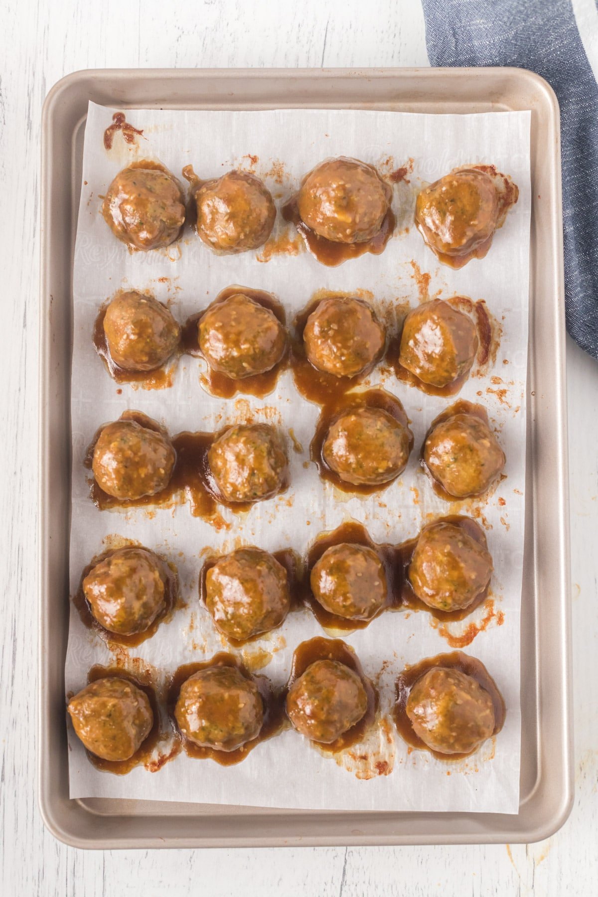 Baked turkey meatballs covered in teriyaki sauce on a baking sheet