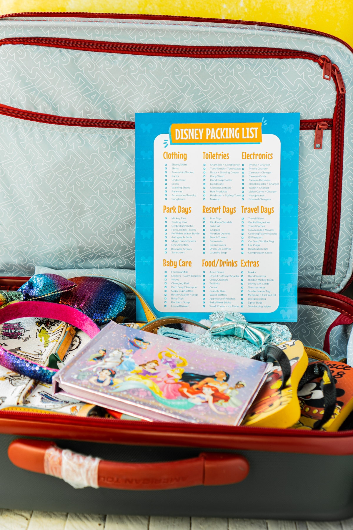 Disney packing list on top of a suitcase full of Disney items