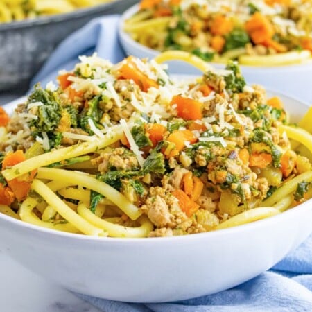 A horizontal bowl of ground turkey pasta with kale and carrots