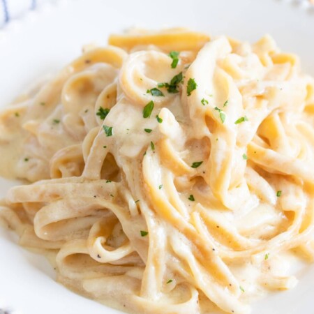 A close-up top down view of a plate full of Instant Pot fettuccine alfredo on a white plate