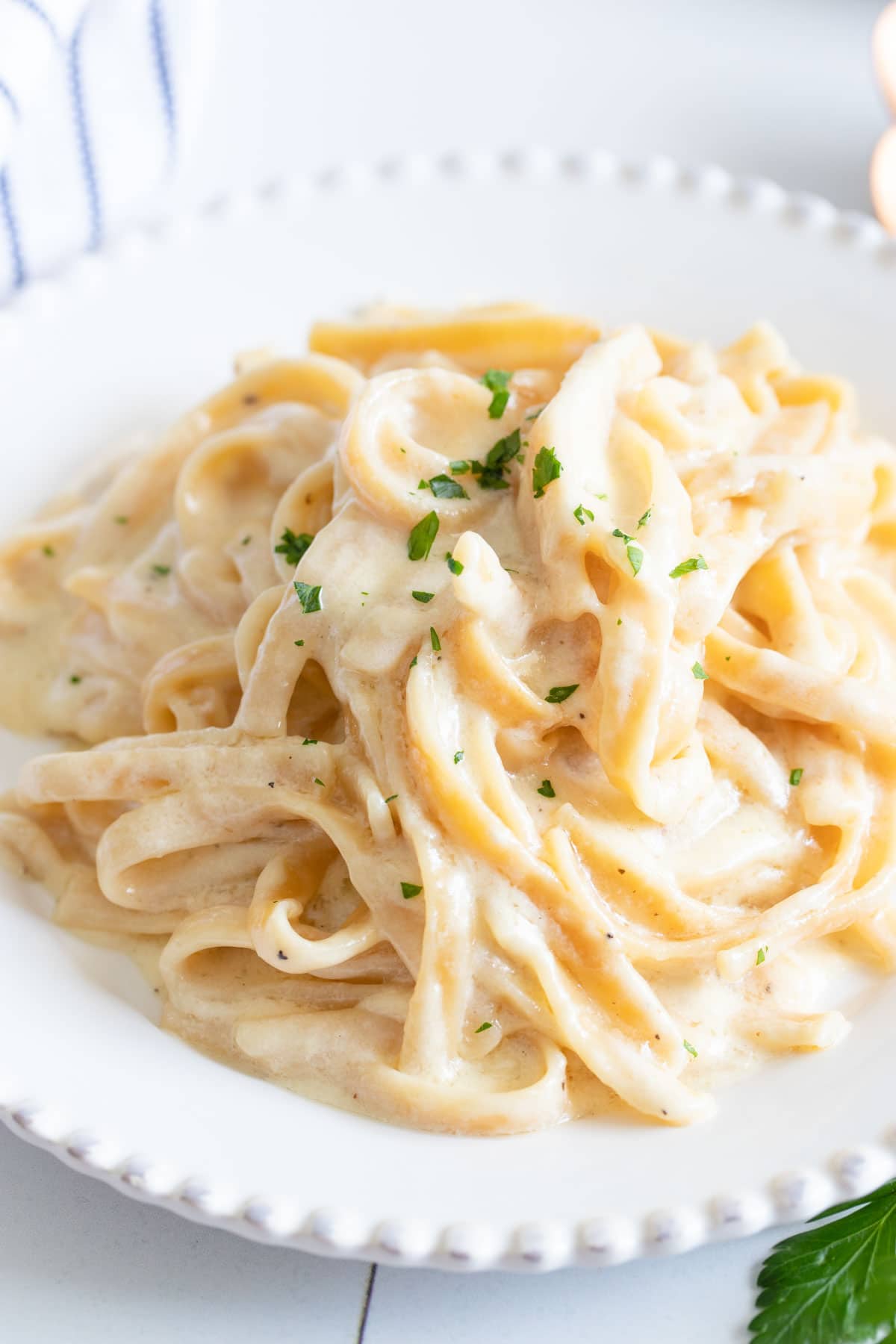 A close-up top down view of a plate full of Instant Pot fettuccine alfredo on a white plate