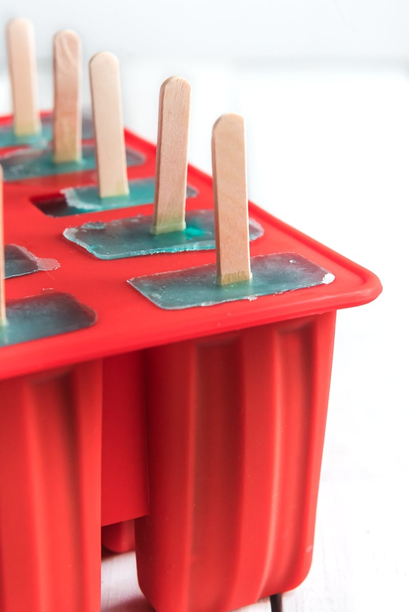Red popsicle molds with blue lemonade popsicles in them