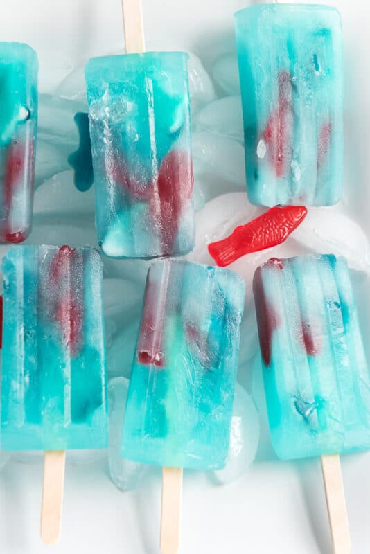 Six blue lemonade popsicles on sticks with gummy fish