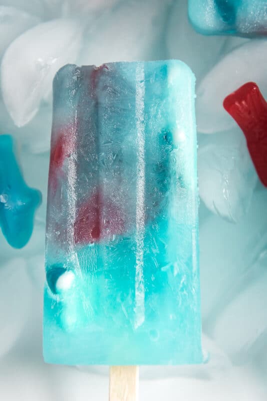 One blue lemonade popsicle on ice with gummy fish inside