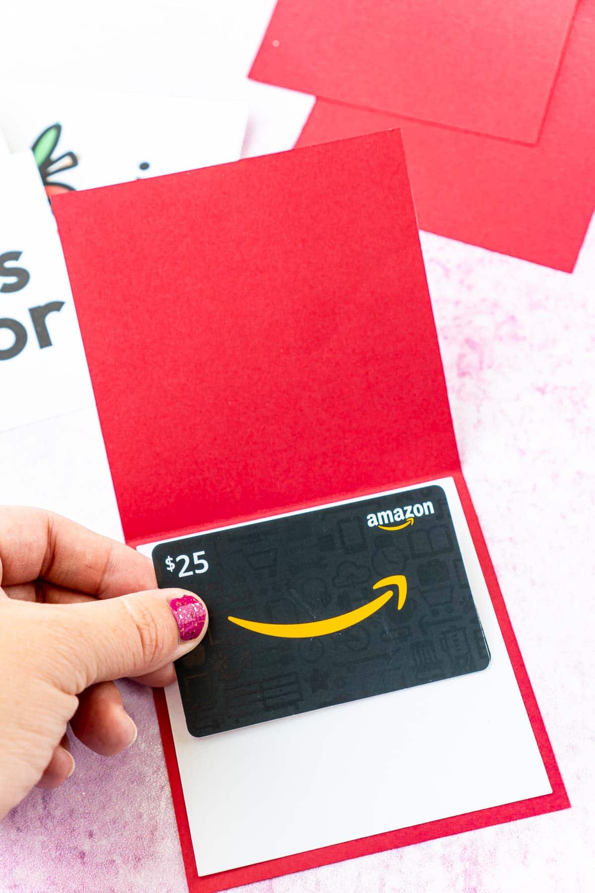 Woman's hand adding a gift card to a red card