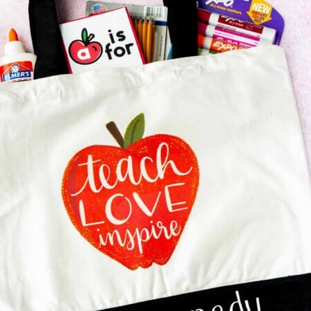 A tote bag with an apple and school supplies sticking out