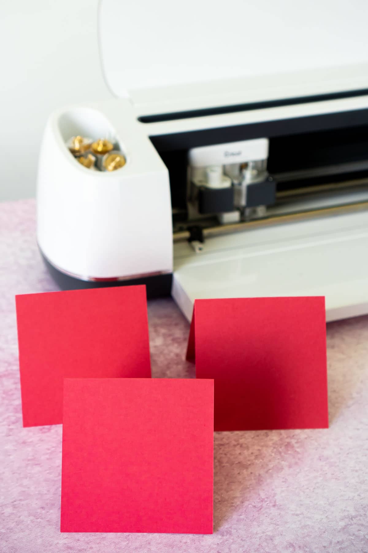 Three pieces of red cardstock cut and folded into front of a Cricut Maker