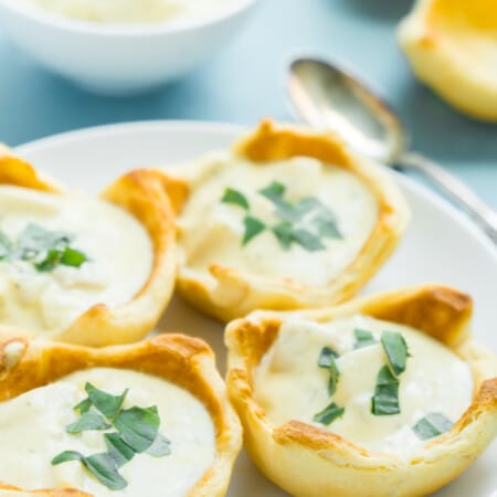 Four bread bowls with soup on them with a blue background