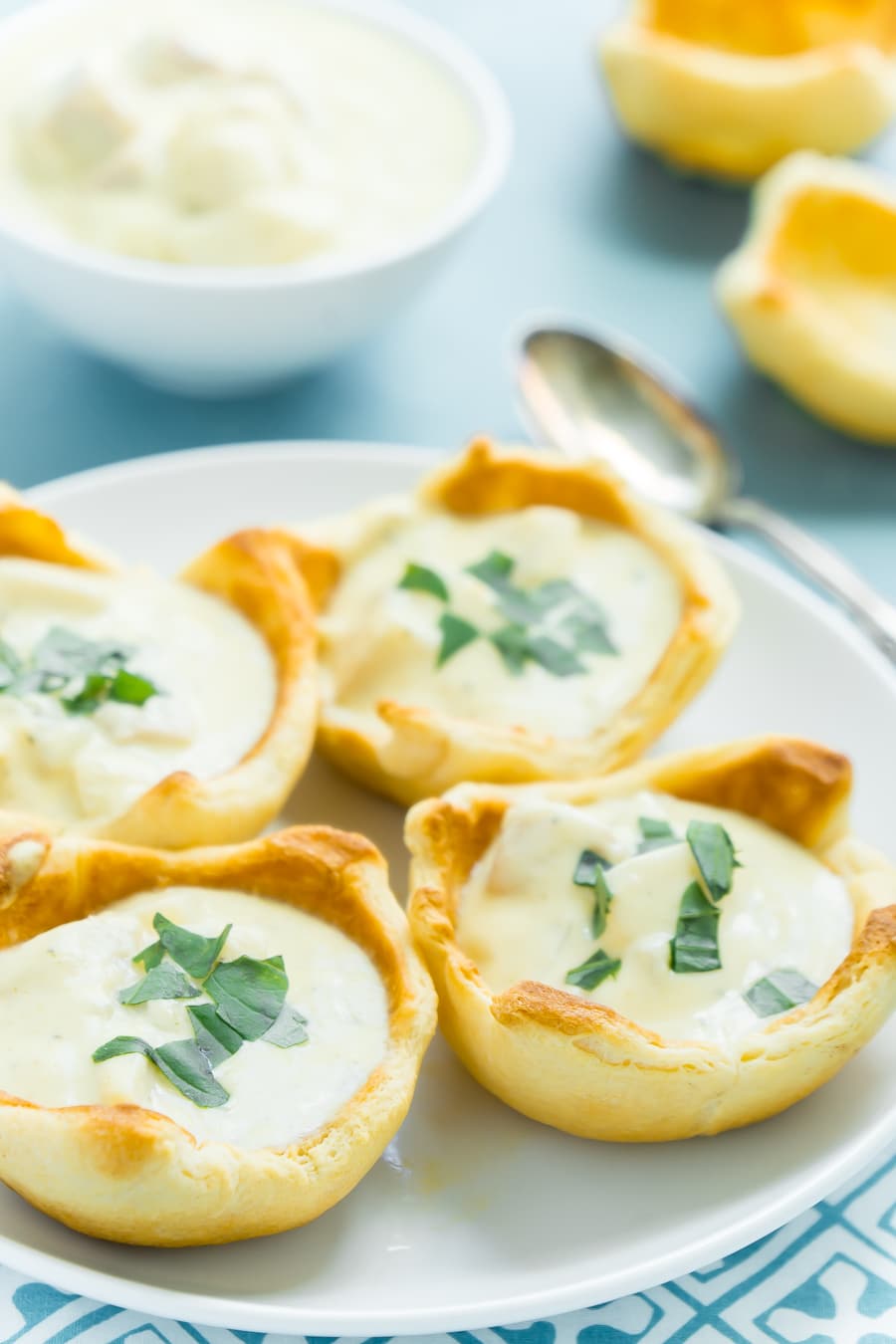 Four bread bowls with soup on them with a blue background