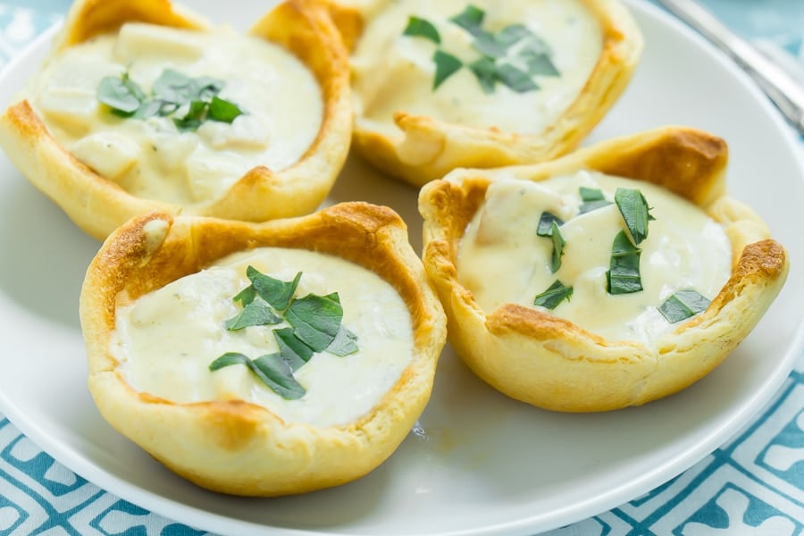 Four bread bowls with chowder on a white plate