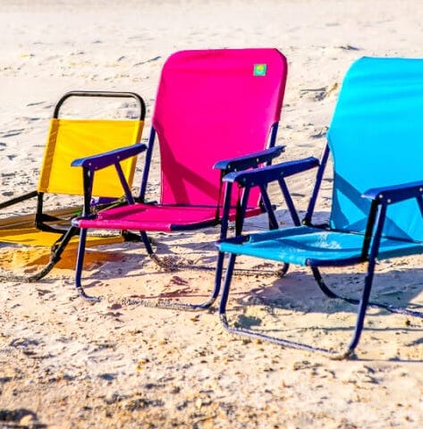 3 colorful beach chairs sitting on a beach