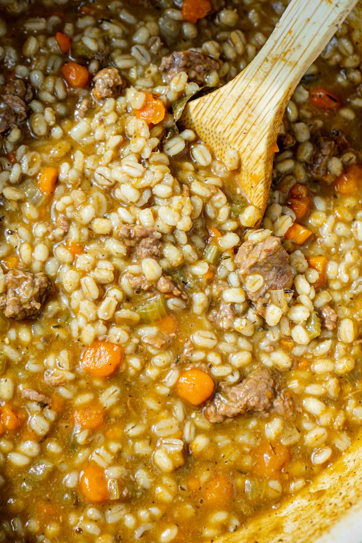 Wooden spoon in a pot of beef and barley soup