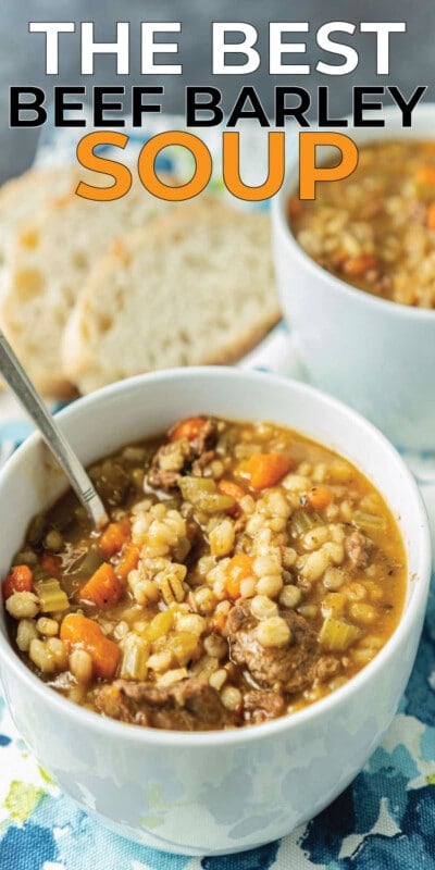 Two white bowls full of beef barley soup with bread in the background with text for Pinterest