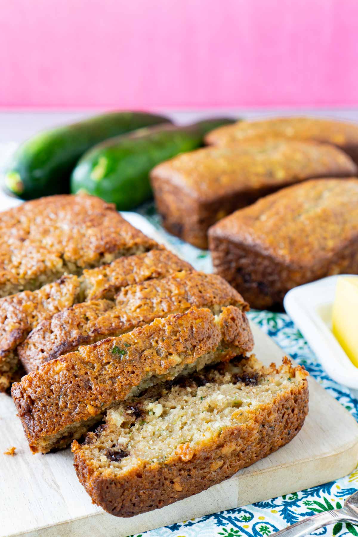 Sliced loaf of chocolate chip zucchini bread with mini loaves and zucchini in the background