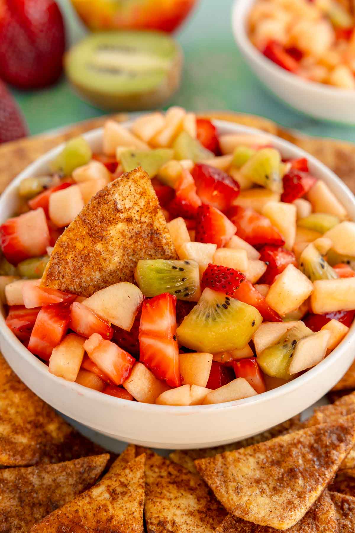 white bowl of fruit salsa with cinnamon chips around it