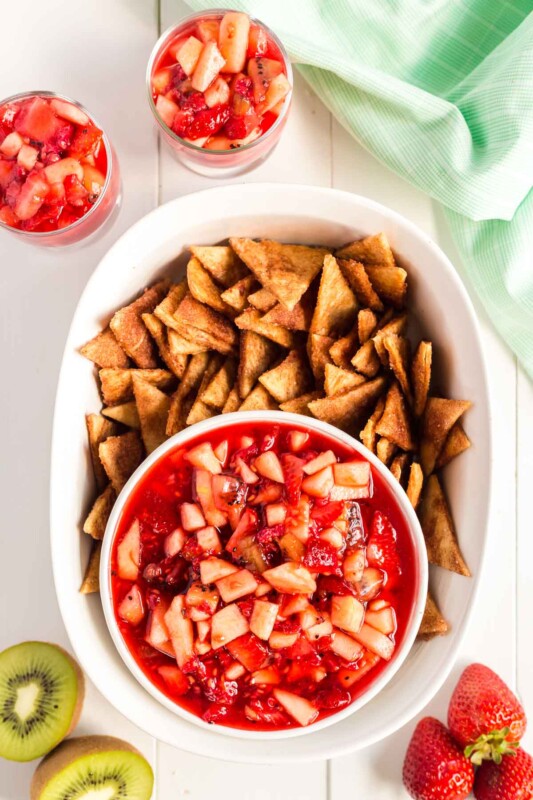 White bowl full of homemade cinnamon chips with a white bowl of fruit salsa