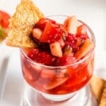 A small glass cup of fruit salsa with a cinnamon chip stuck in it