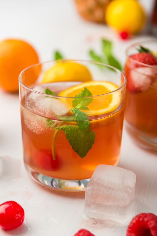 A glass of homemade fruit punch with oranges and ice cubes