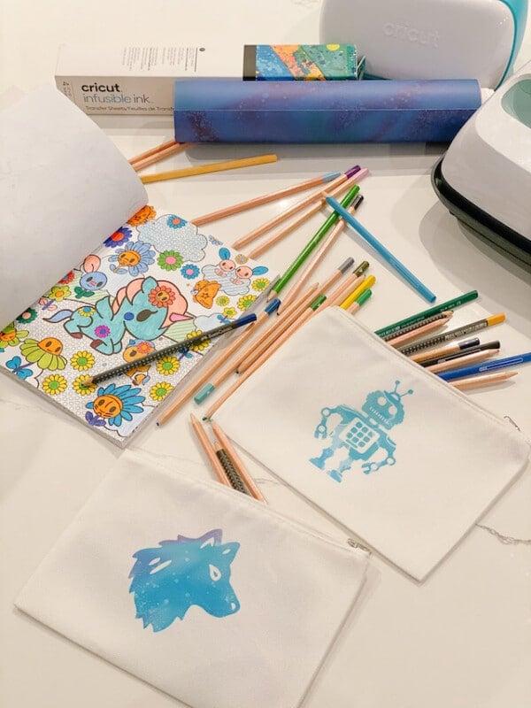 White school supply bags with a wolf and robot on them with pencils strewn about