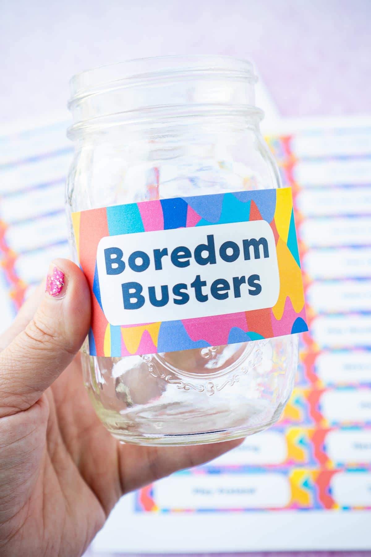 Woman's hand holding a jar with a boredom busters label on the front