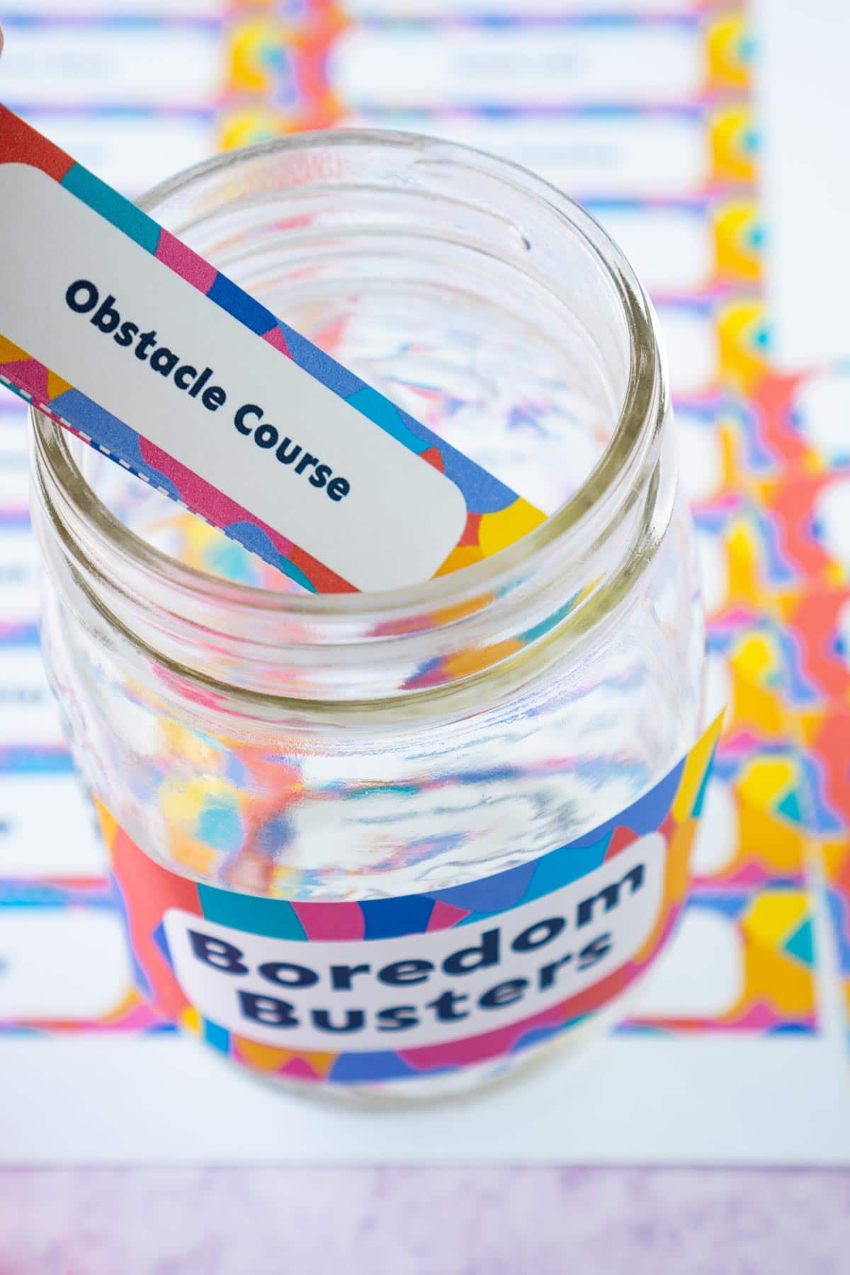 A paper that says obstacle course being placed into a glass jar
