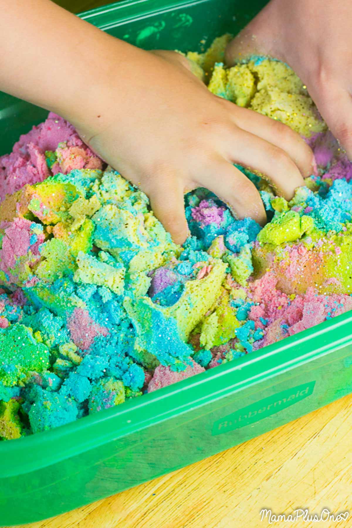 Kid playing in rainbow colored kinetic sand