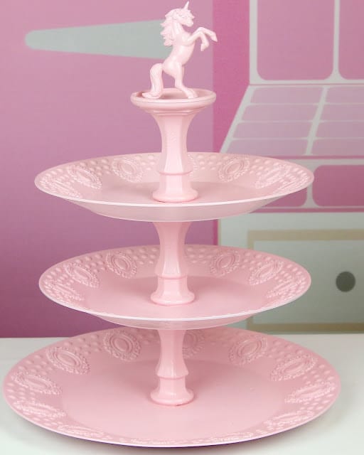 A pink cupcake stand with a unicorn on top