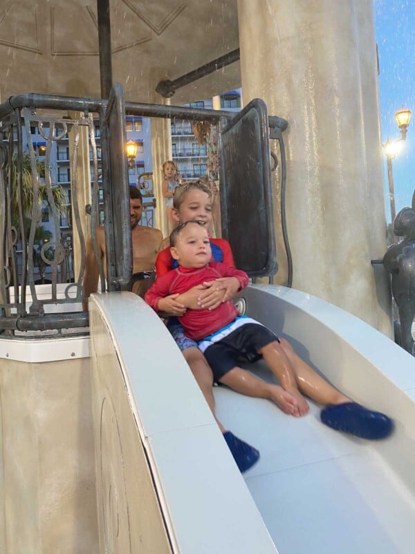 Two boys riding a water slide together